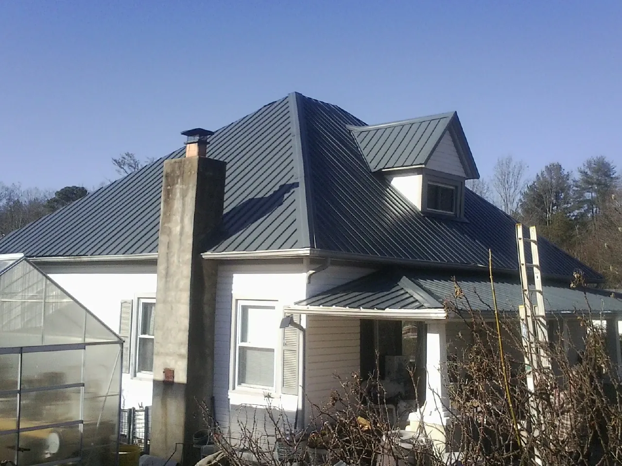 Dark blue standing seam metal roof on a white farmhouse with dormer — Slate & Tile Roof Repair by Roofing Brothers in Cochranton