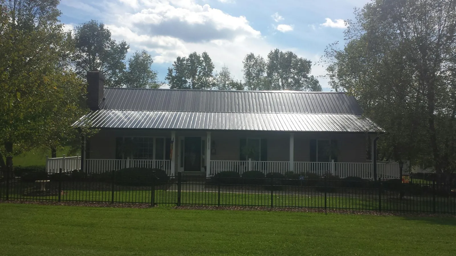 Gray metal roof on a brick ranch with a full width front porch — Gutter Guard Installation work by our crew in Cochranton