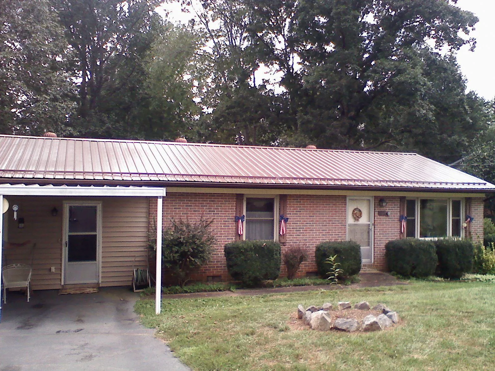 Bronze metal roof and carport on a brick ranch home — Roof Repair work by our crew in Cochranton