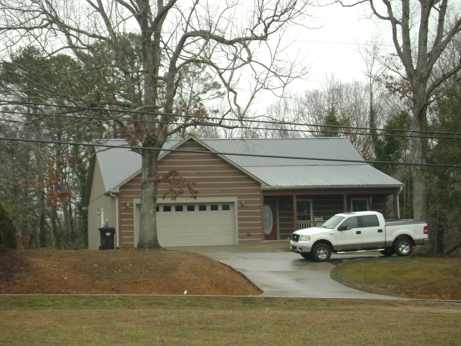 Gray metal roof on a log sided house with an attached two car garage in Cochranton