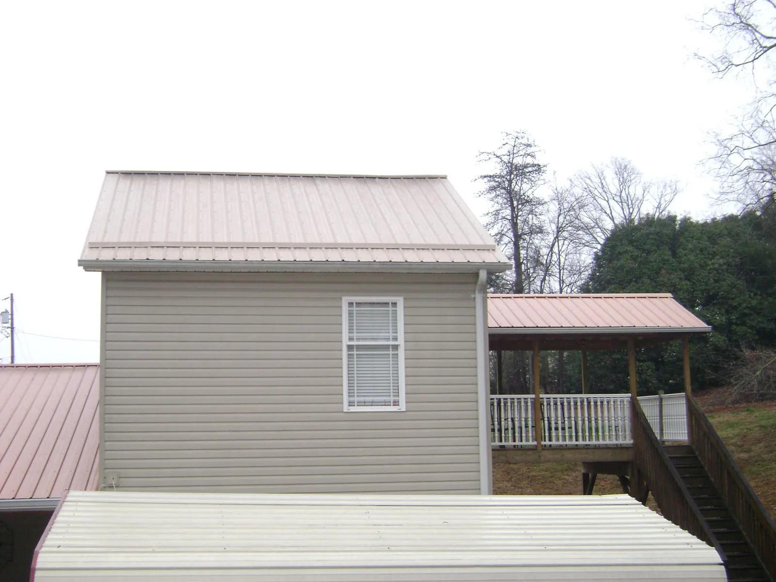 Tan metal roofs on a two story addition and attached porch, from a Roof Replacement job in Cochranton